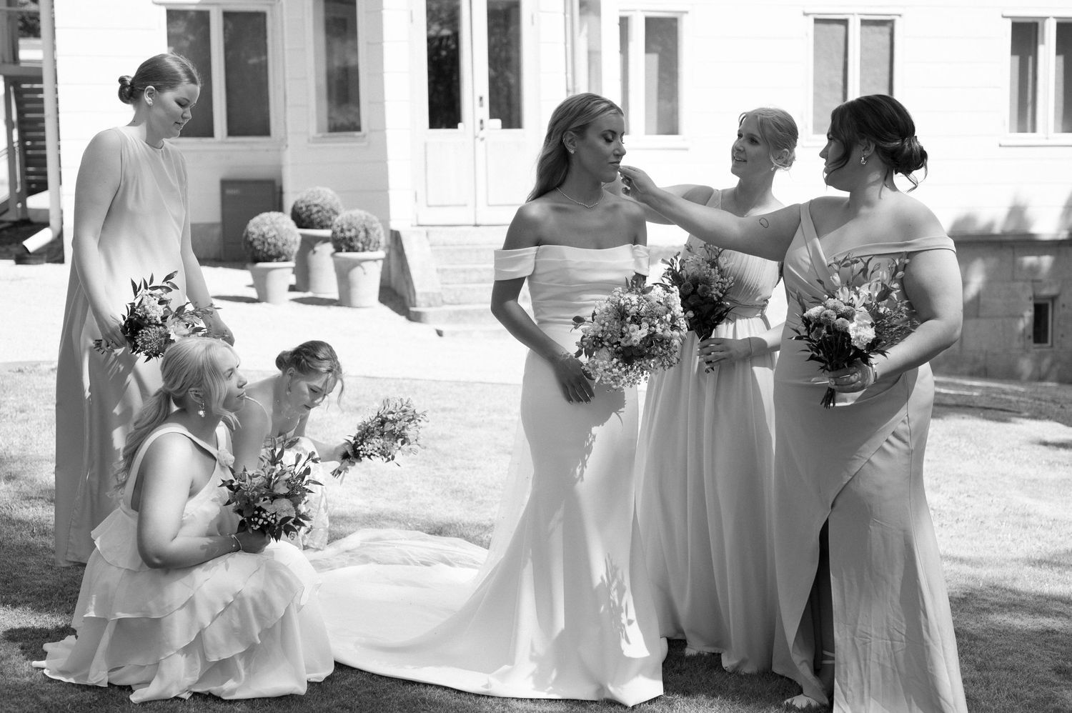 Bridesmaids in pink dresses share candid moment during outdoor wedding celebration.