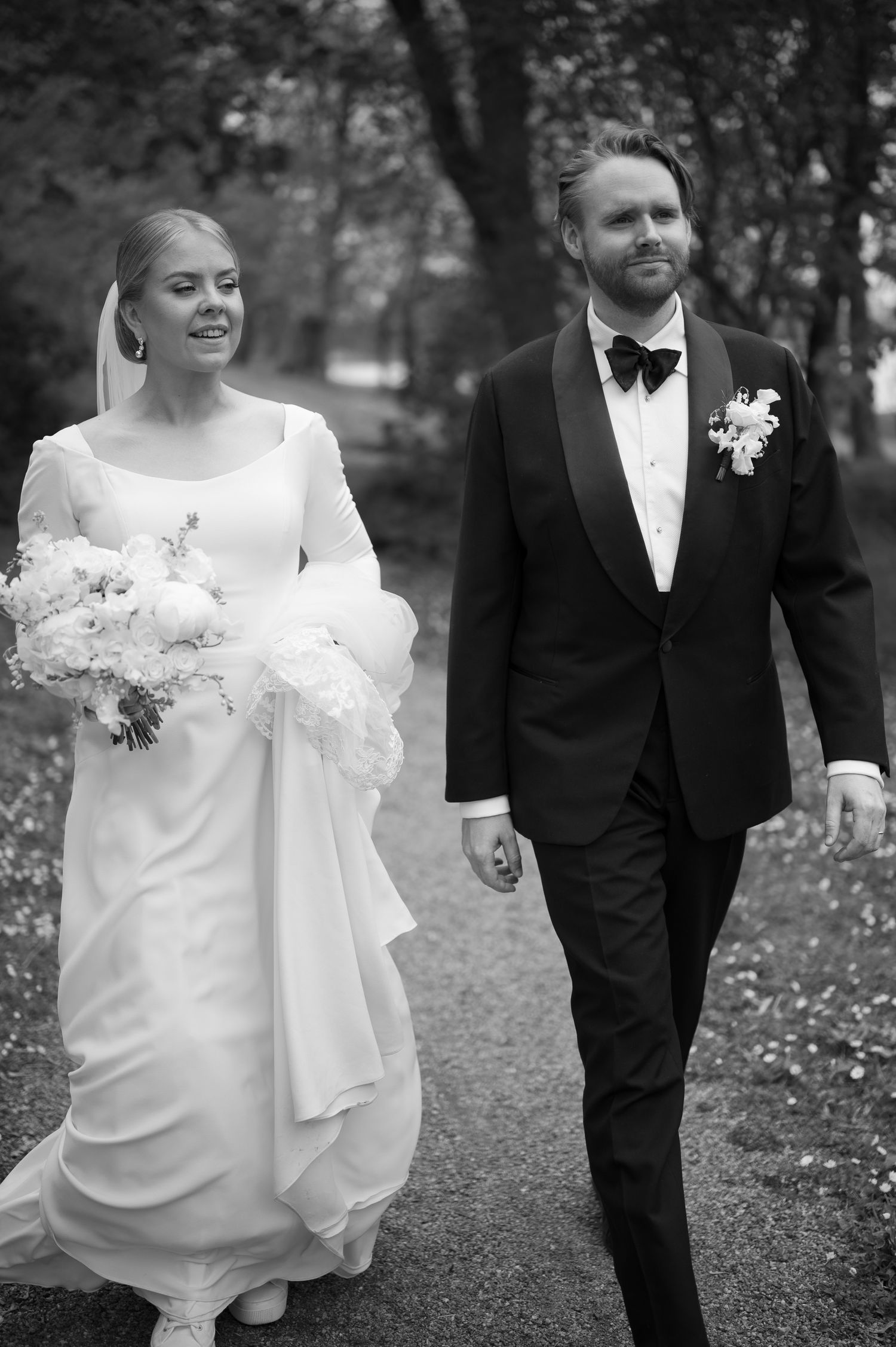 Black and white wedding photos show a couple walking together outdoors in formal attire with the bride in a flowing dress.