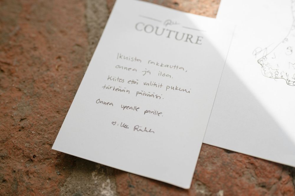 Wedding stationery with couture branding displayed on textured surface.