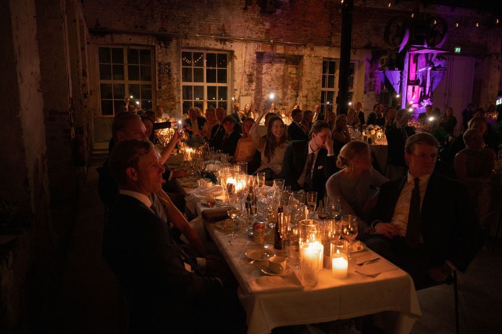 Moody candlelit wedding reception venue with purple uplighting and guests seated at long tables.
