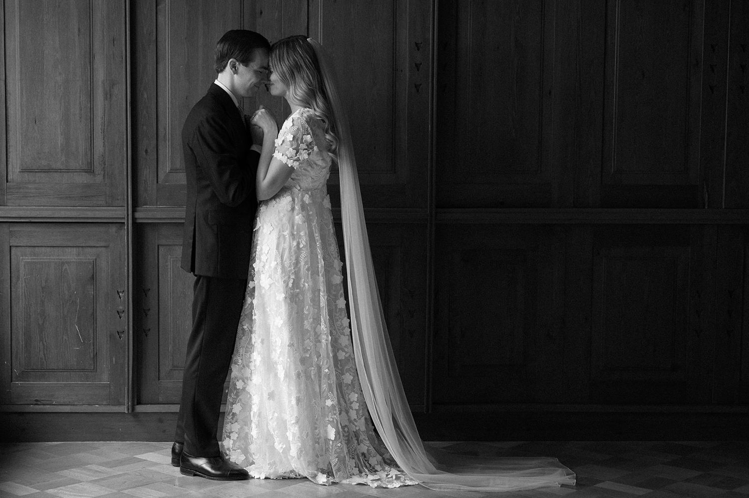 Black and white romantic wedding moment captured in an elegant indoor setting.