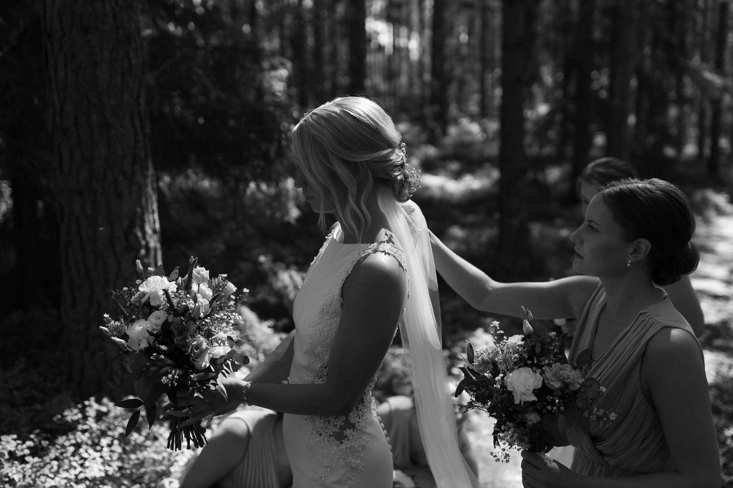 Black and white candid moments of a wedding party in a forest setting.