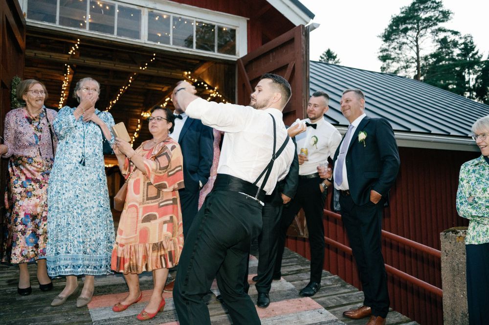 Wedding celebration outside a red barn with guests dancing and mingling.