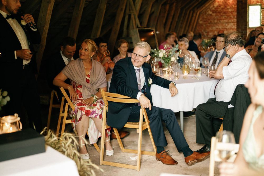 Wedding guests enjoying a festive reception celebration in a rustic barn venue with string lights overhead.