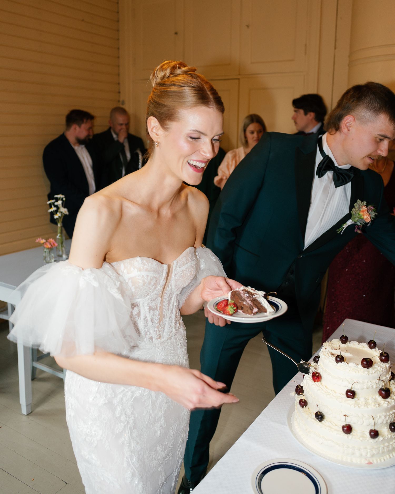 Wedding celebration with white cake and cherry decorations being served.