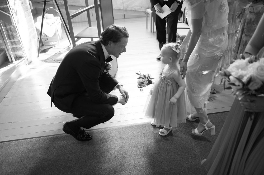 Low-angle black and white shot of someone adjusting a wedding dress train.