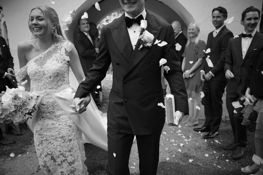 Black and white capture of joyful wedding exit with confetti shower.