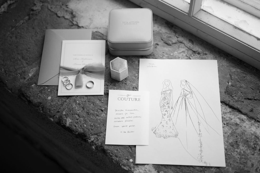 Wedding dress sketches and rings arranged artistically by window light.