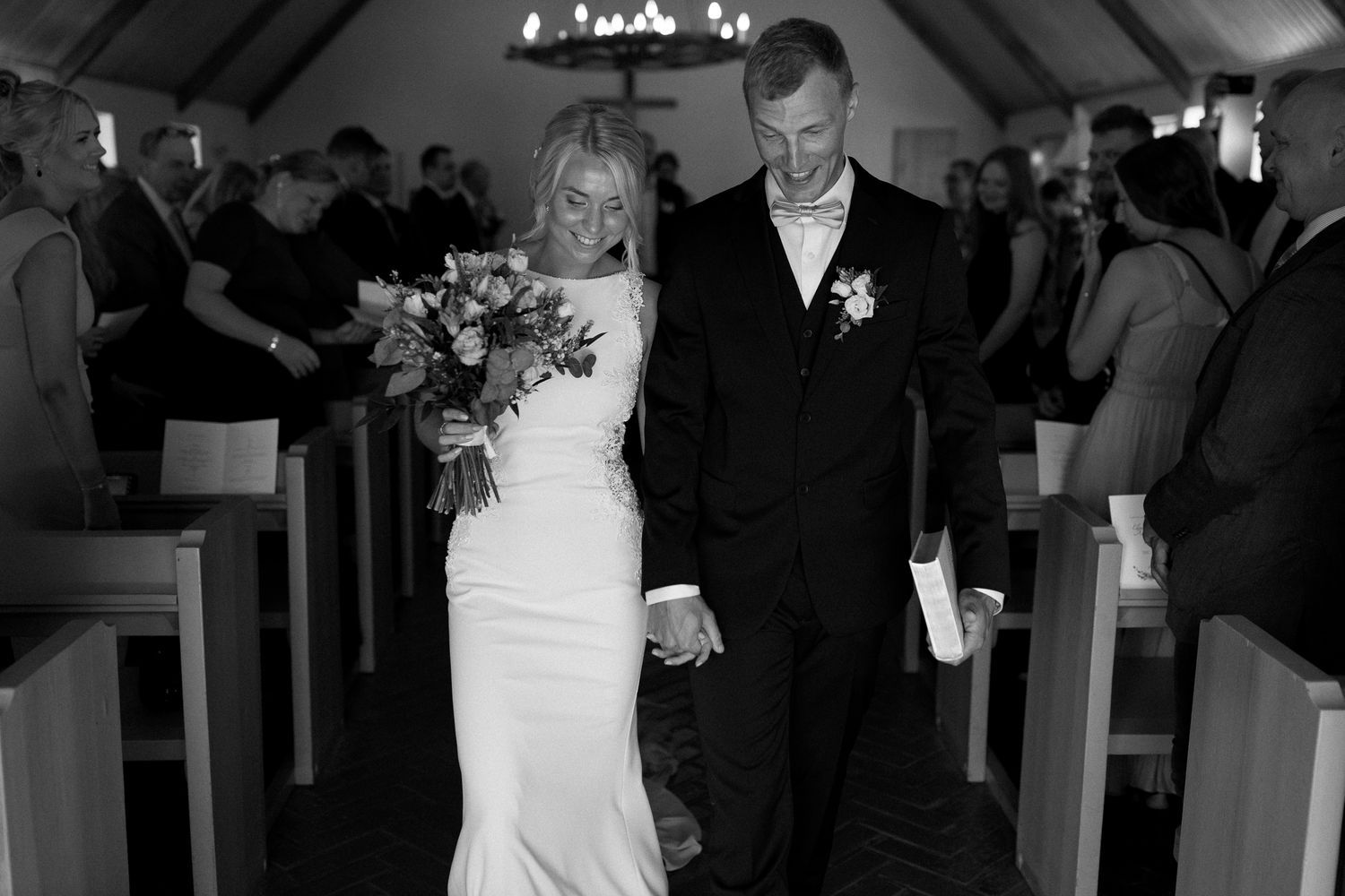 Black and white photo of a wedding ceremony in a chapel with vaulted ceilings.