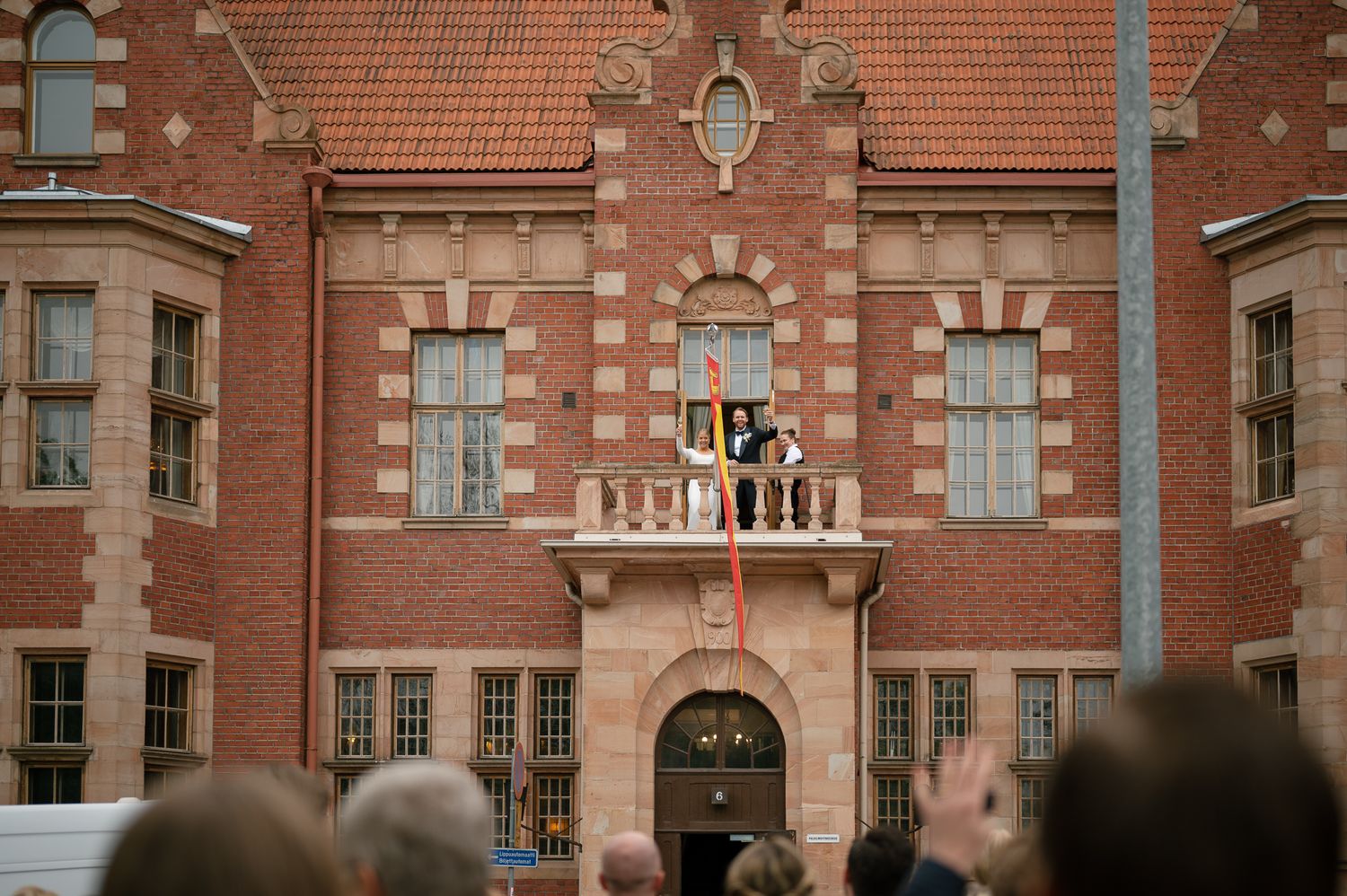 Historic red brick university building with ornate architecture and stone trim details under cloudy skies.
