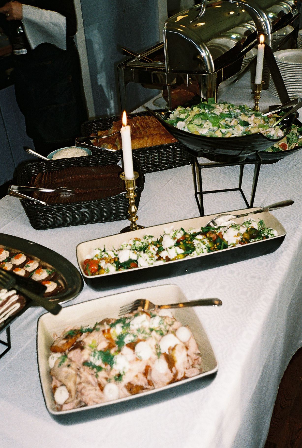 Wedding buffet table with white platters of food and elegant serving dishes.