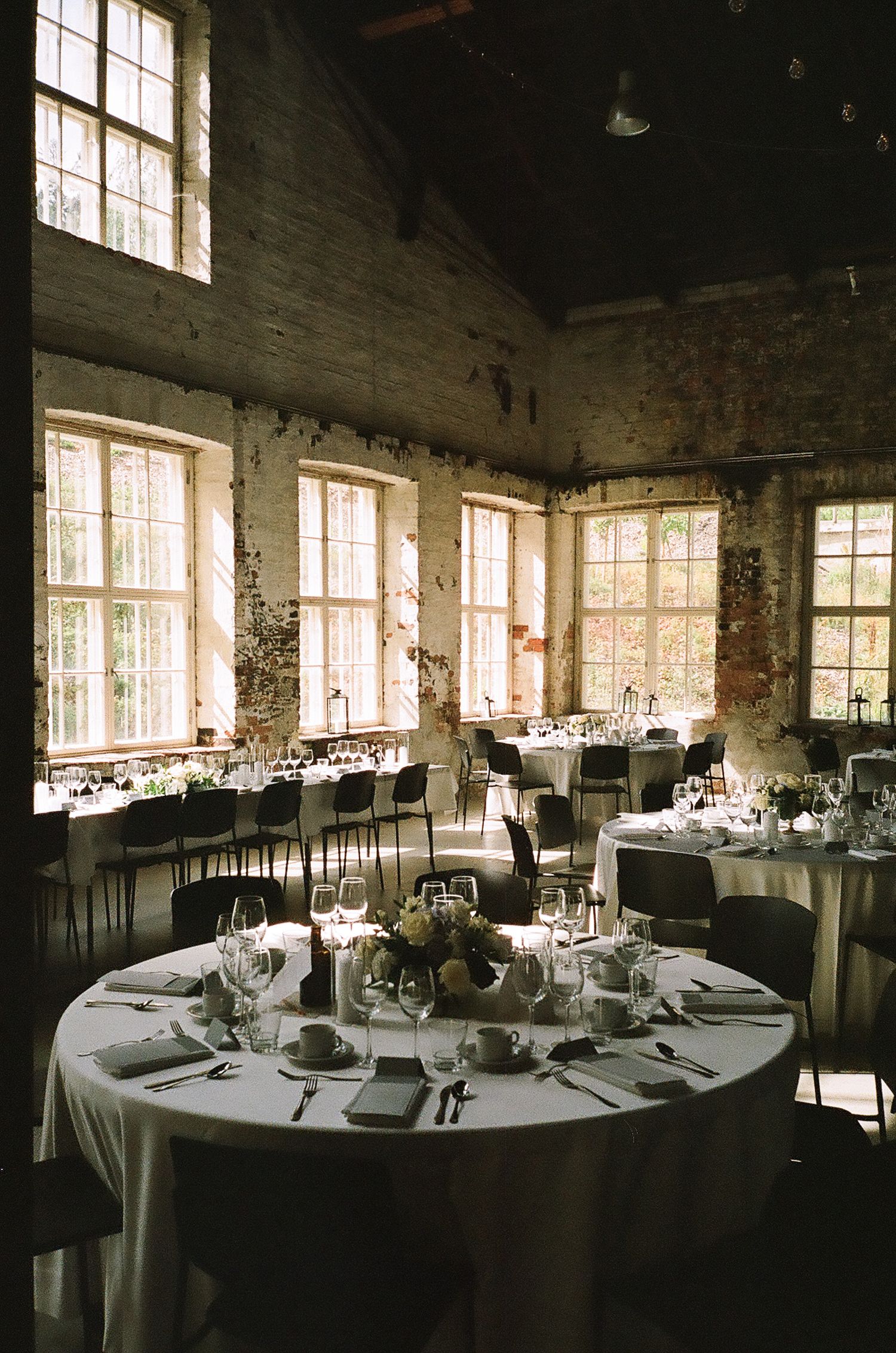 Industrial-style wedding venue with exposed brick walls and round tables set for reception.