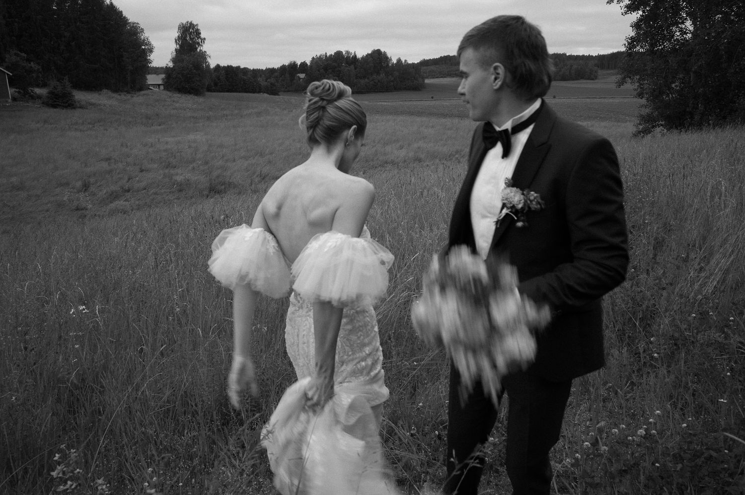 Couple in formal attire embracing in an outdoor field setting.