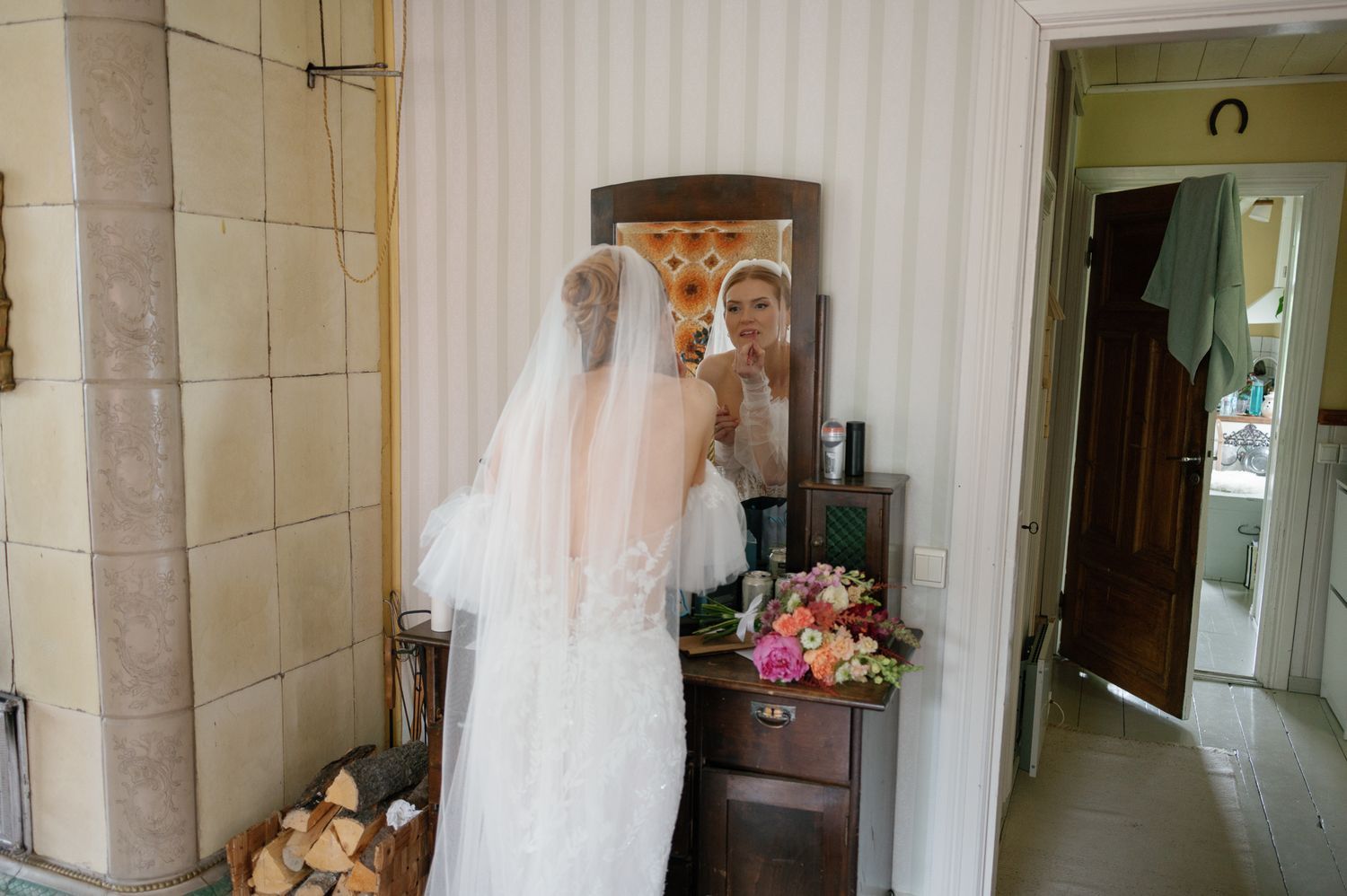 Long hallway with white walls and vintage mirrors leading to wedding venue.