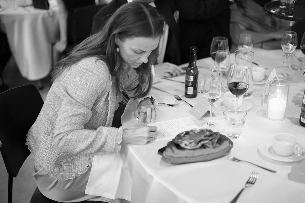 Guests dining at elegant white-clothed tables during a wedding reception.