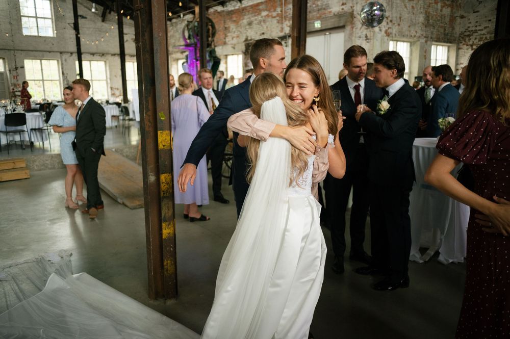 Wedding guests gather in an industrial-chic venue with exposed brick walls and high ceilings.