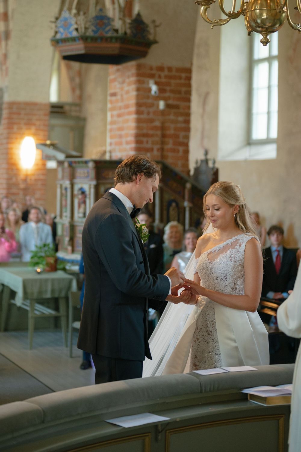 A couple exchanges rings during their wedding ceremony in a beautiful brick church interior.