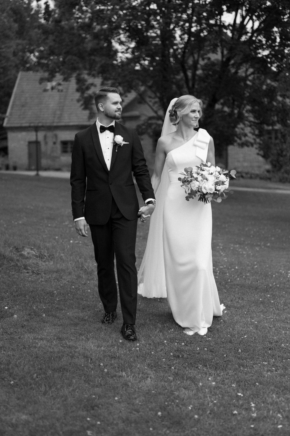 A classic black and white wedding portrait captured on a grassy lawn.