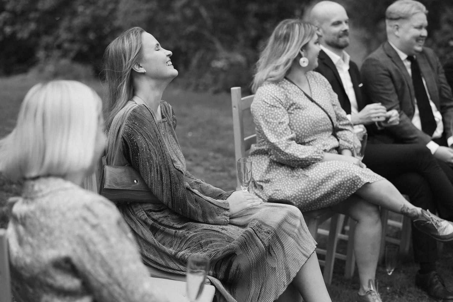 Black and white photo of guests reacting with joy during an outdoor event.