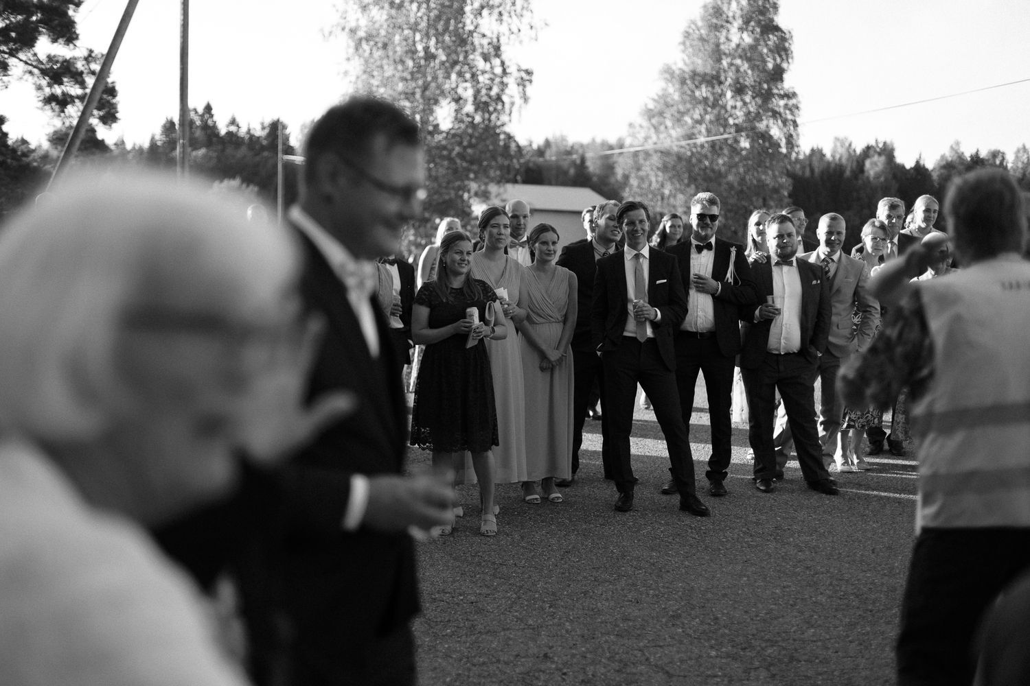 Wedding guests gather in distance during outdoor ceremony at dusk.