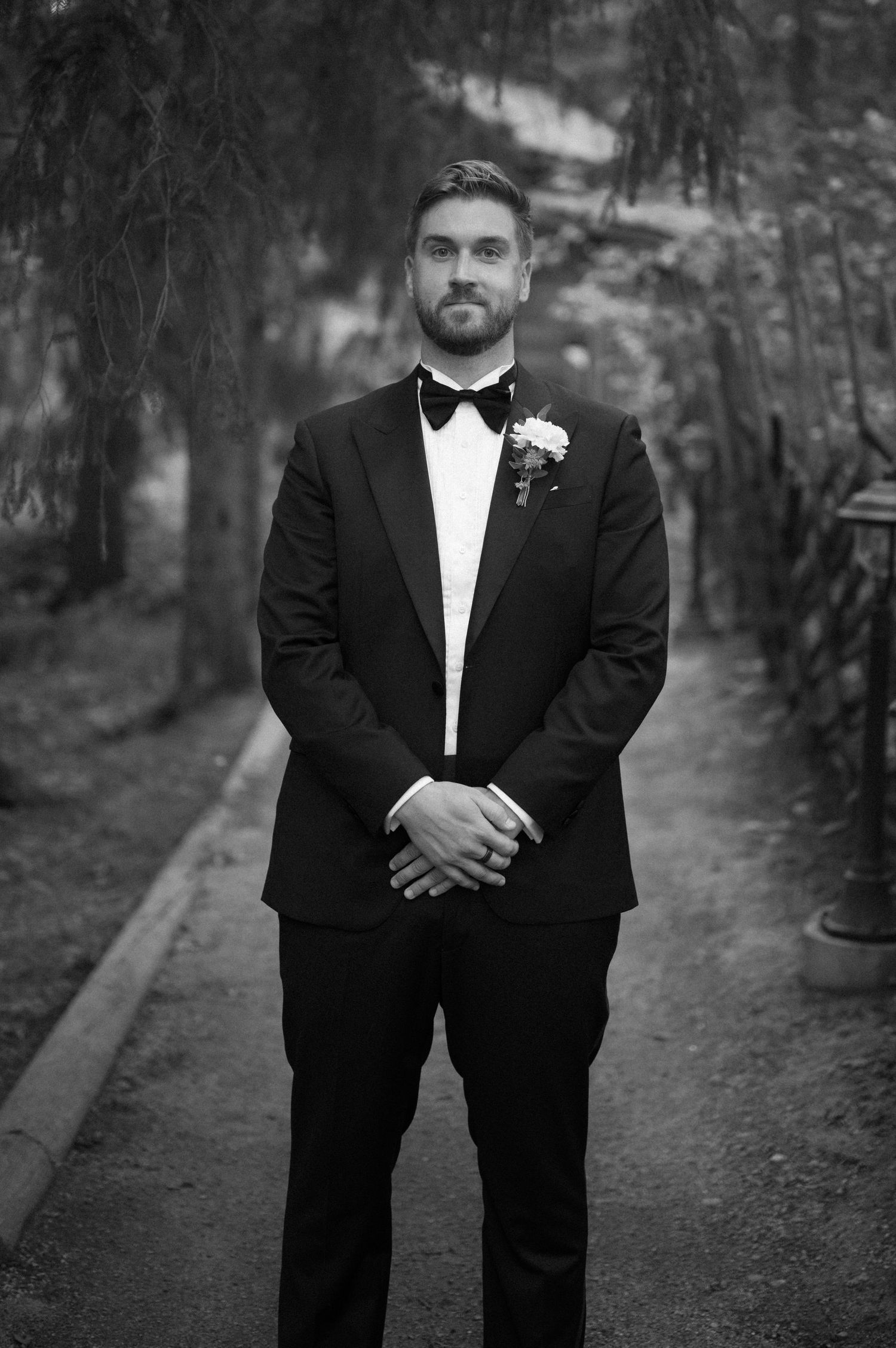 Black and white portrait of groomsmen in formal attire on a garden path.