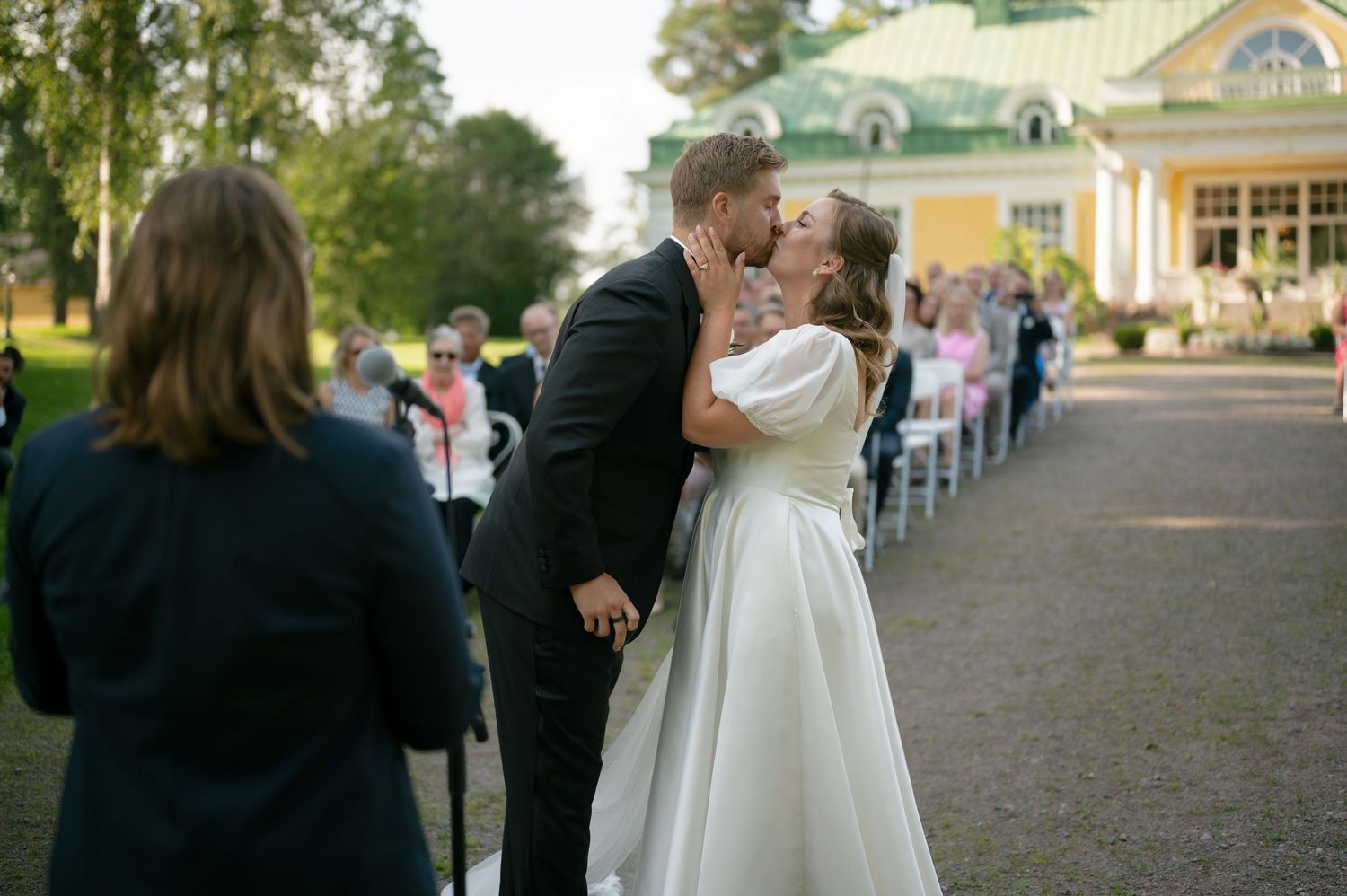 Wedding ceremony procession walking down an aisle with guests seated on both sides.