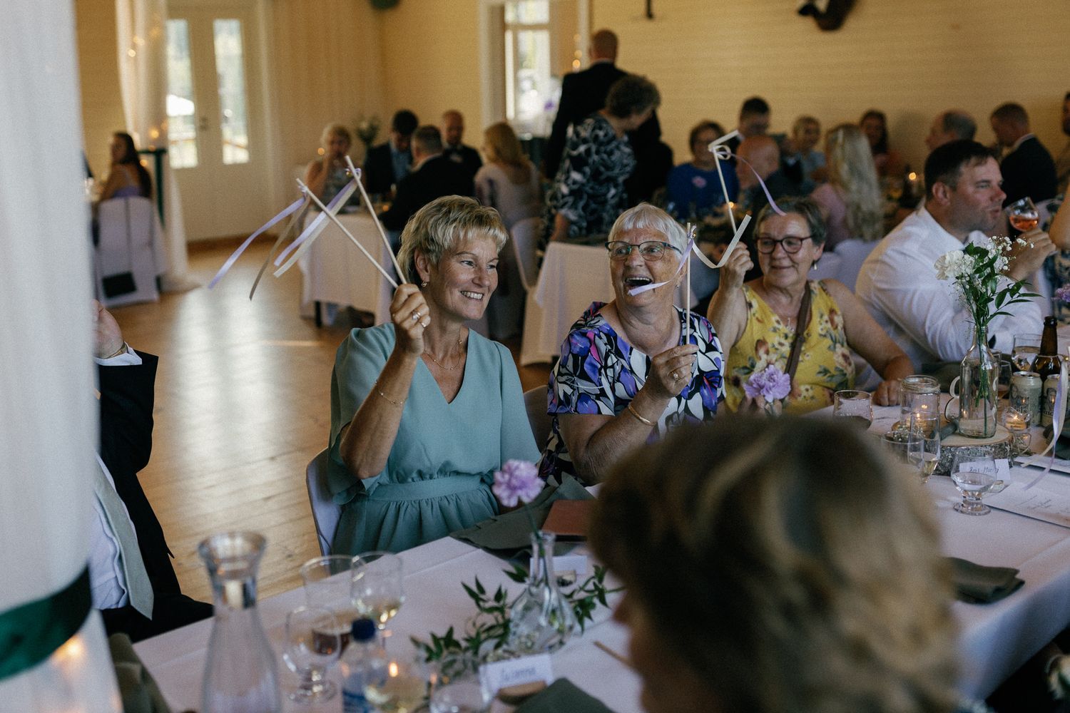 Wedding reception guests seated at decorated tables in a bright venue.