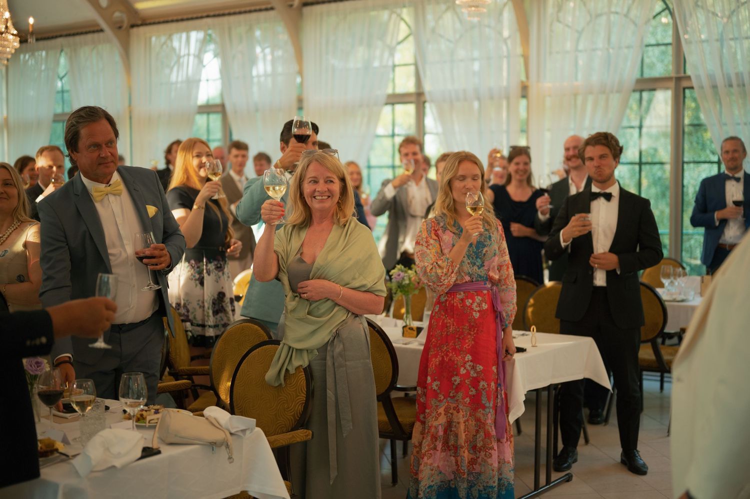 Wedding celebration panorama showing guests enjoying themselves in a sunlit reception venue.