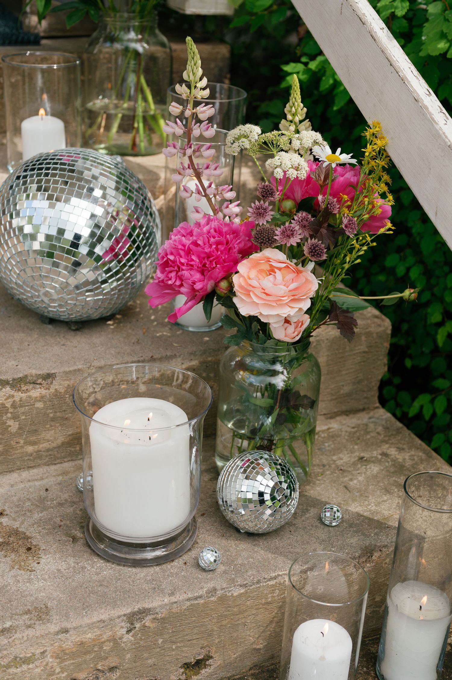 Disco balls and pink flowers create festive decor on rustic wooden surface.