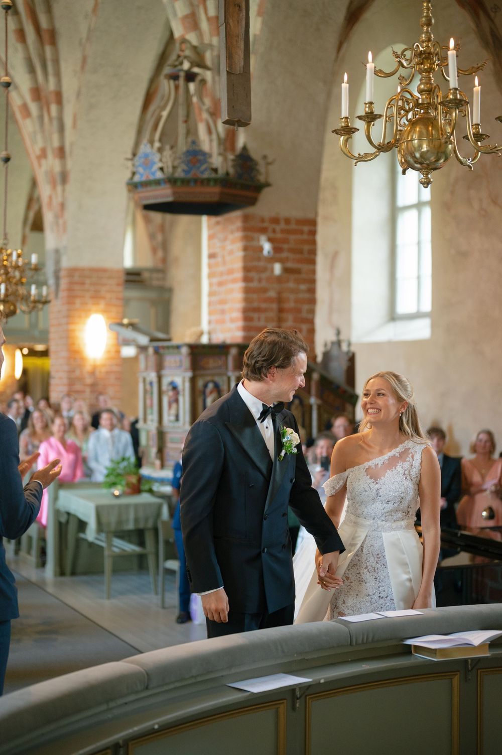 A joyful wedding moment captured under ornate chandeliers in a historic church setting.