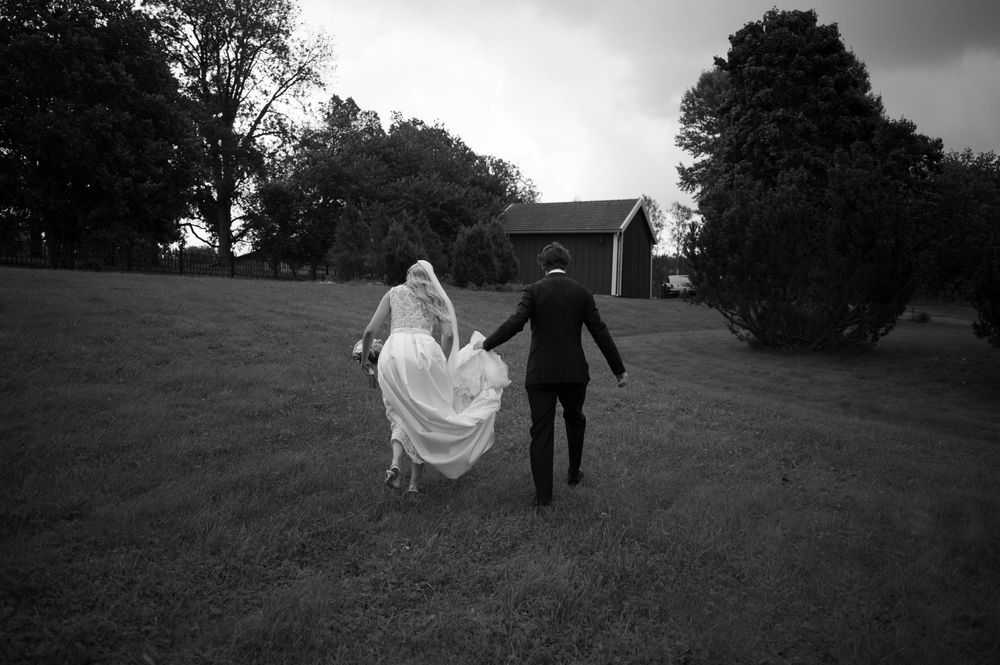 Silhouetted wedding couple walking together across a grassy hillside.