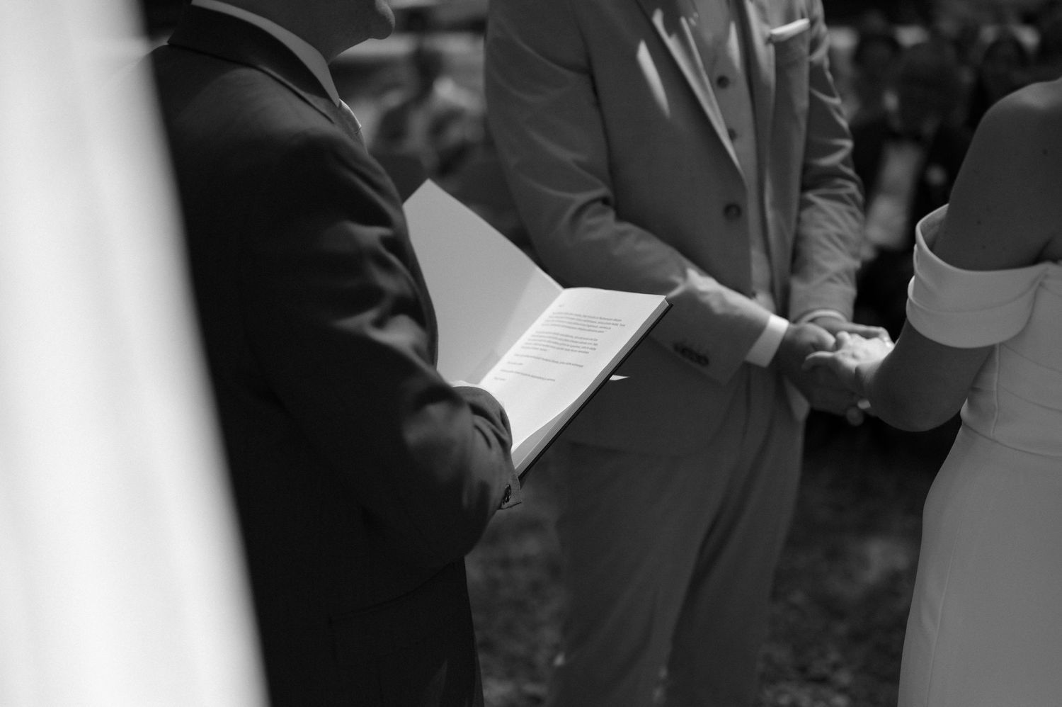 Black and white photo of a wedding ceremony taking place in a wooded outdoor setting.