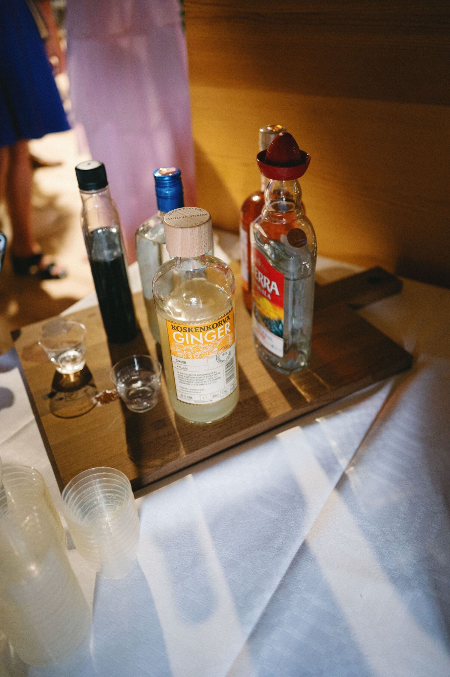 Various liquor bottles and mixers arranged on a wooden bar surface in warm lighting.