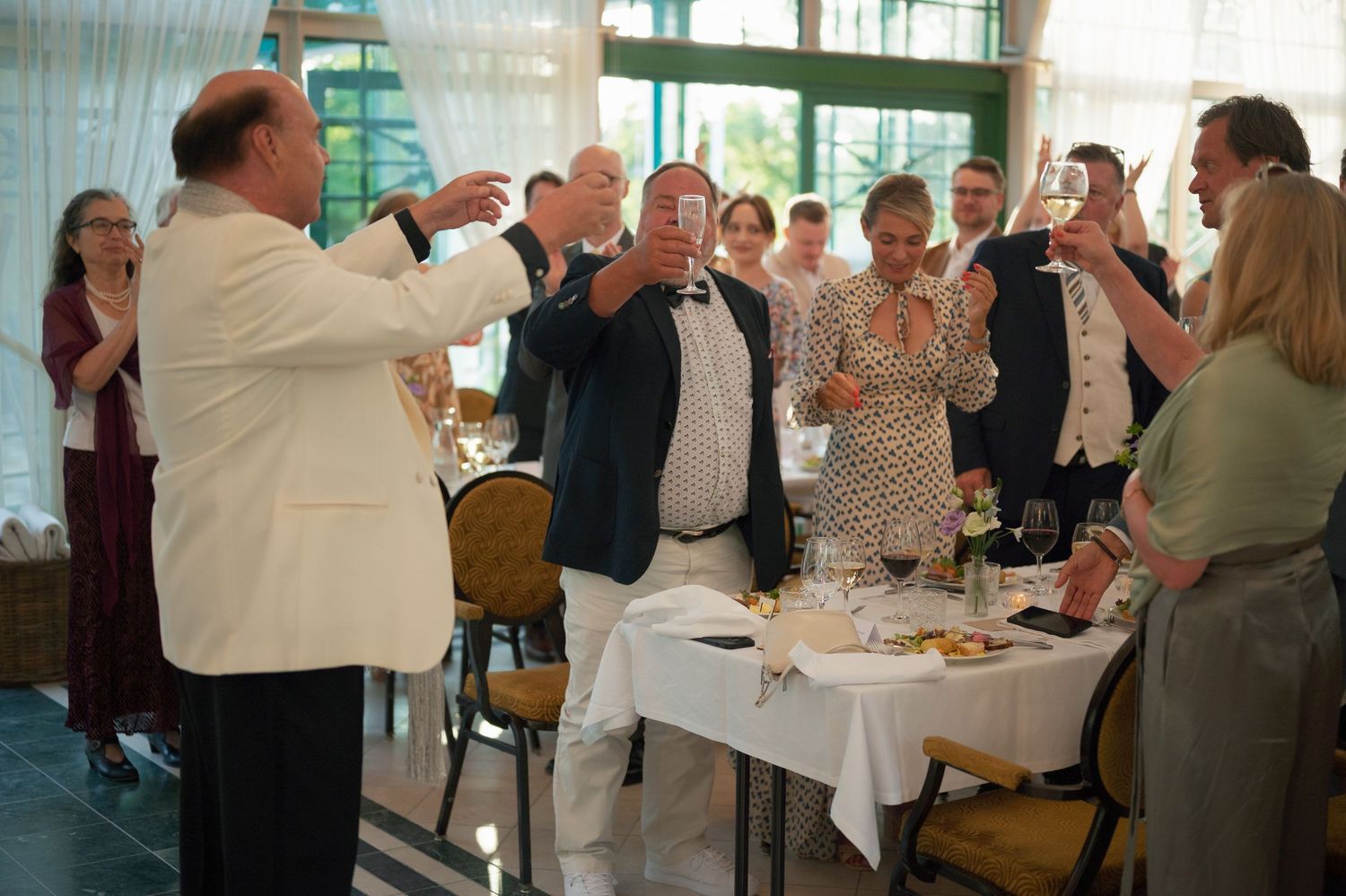 Wedding guests raise their glasses in celebration during a reception toast.