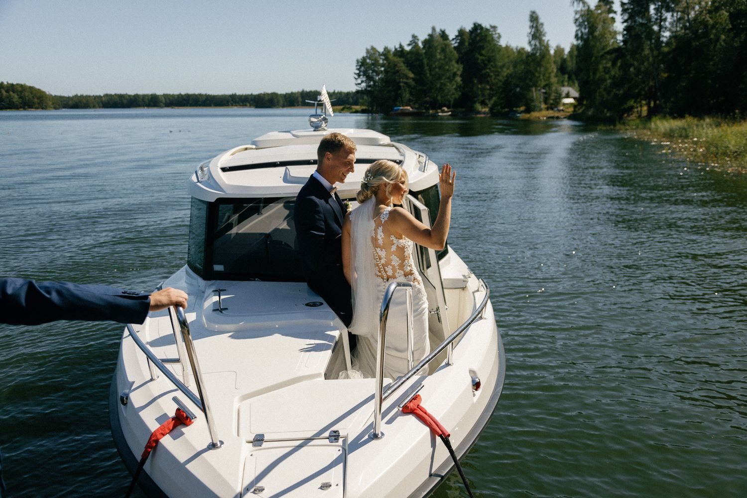 Celebratory moment aboard a white boat on a sunny lake surrounded by forest.