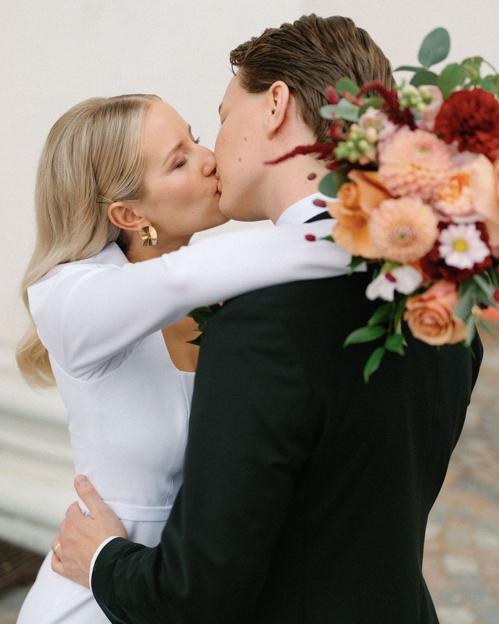 An intimate wedding photo with a beautiful peach and red floral bouquet.
