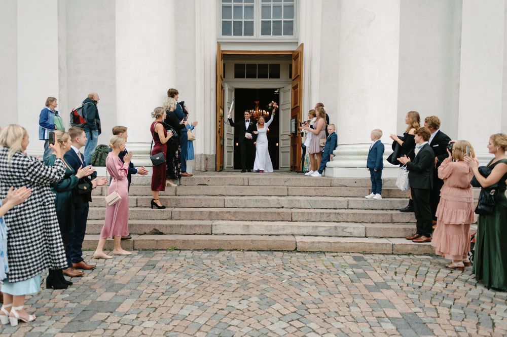 Wedding party and guests celebrating outside a white columned building.