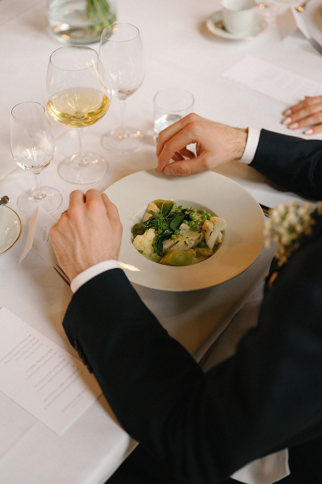 A formal place setting with wine glasses and a salad dish being enjoyed at an elegant dining table.