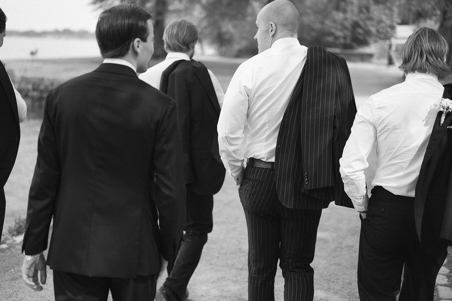 Group of formally dressed wedding guests walking together outdoors.