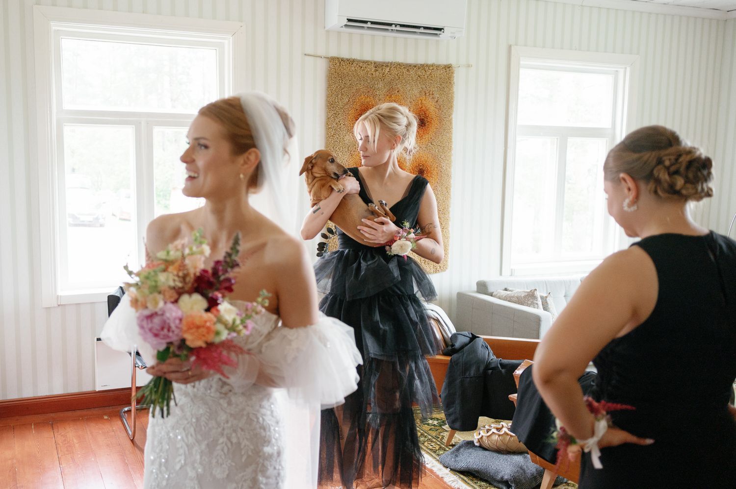 Bridal party getting ready in a sunlit white room with elegant decor.