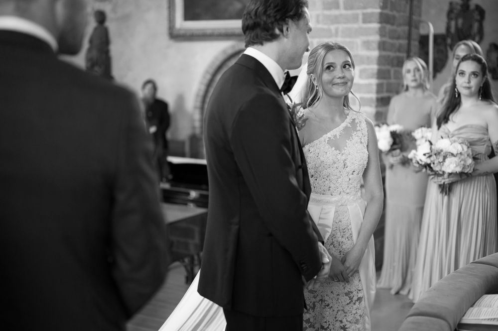 A monochrome wedding photo shows a tender moment between the couple during their ceremony.