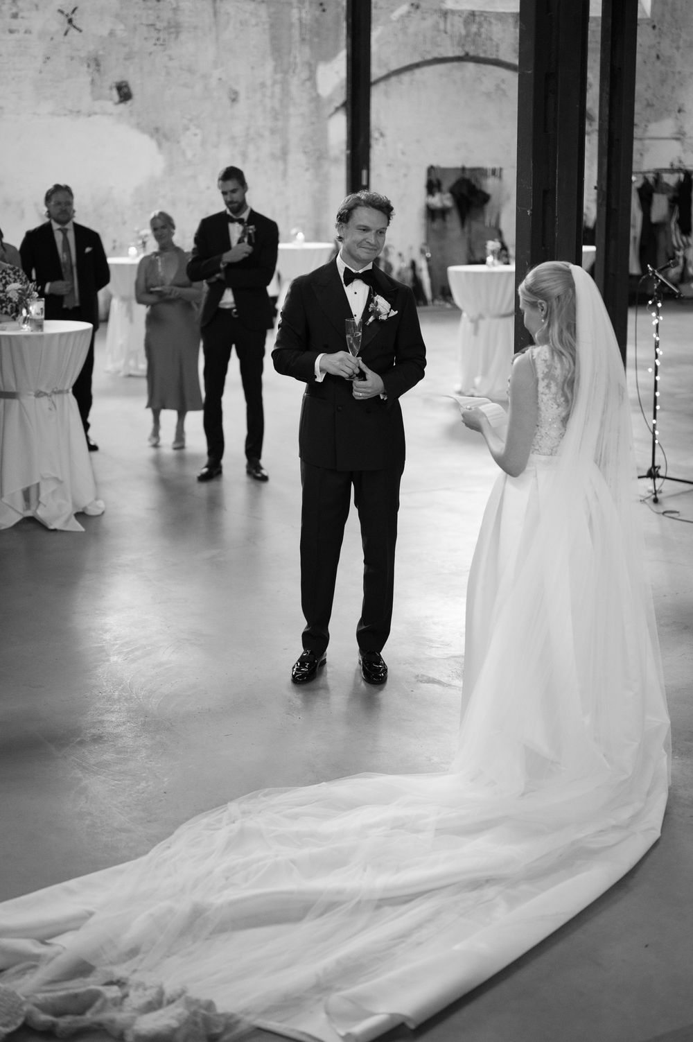 A dramatic wedding dress train trails across an industrial-style floor during a ceremony.