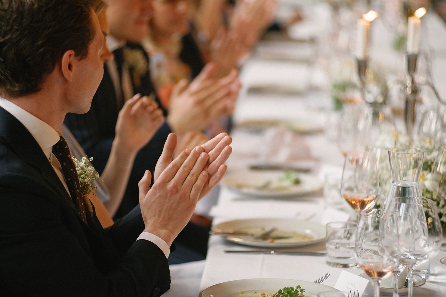 Guests at an elegant dinner event with formal place settings and glassware.