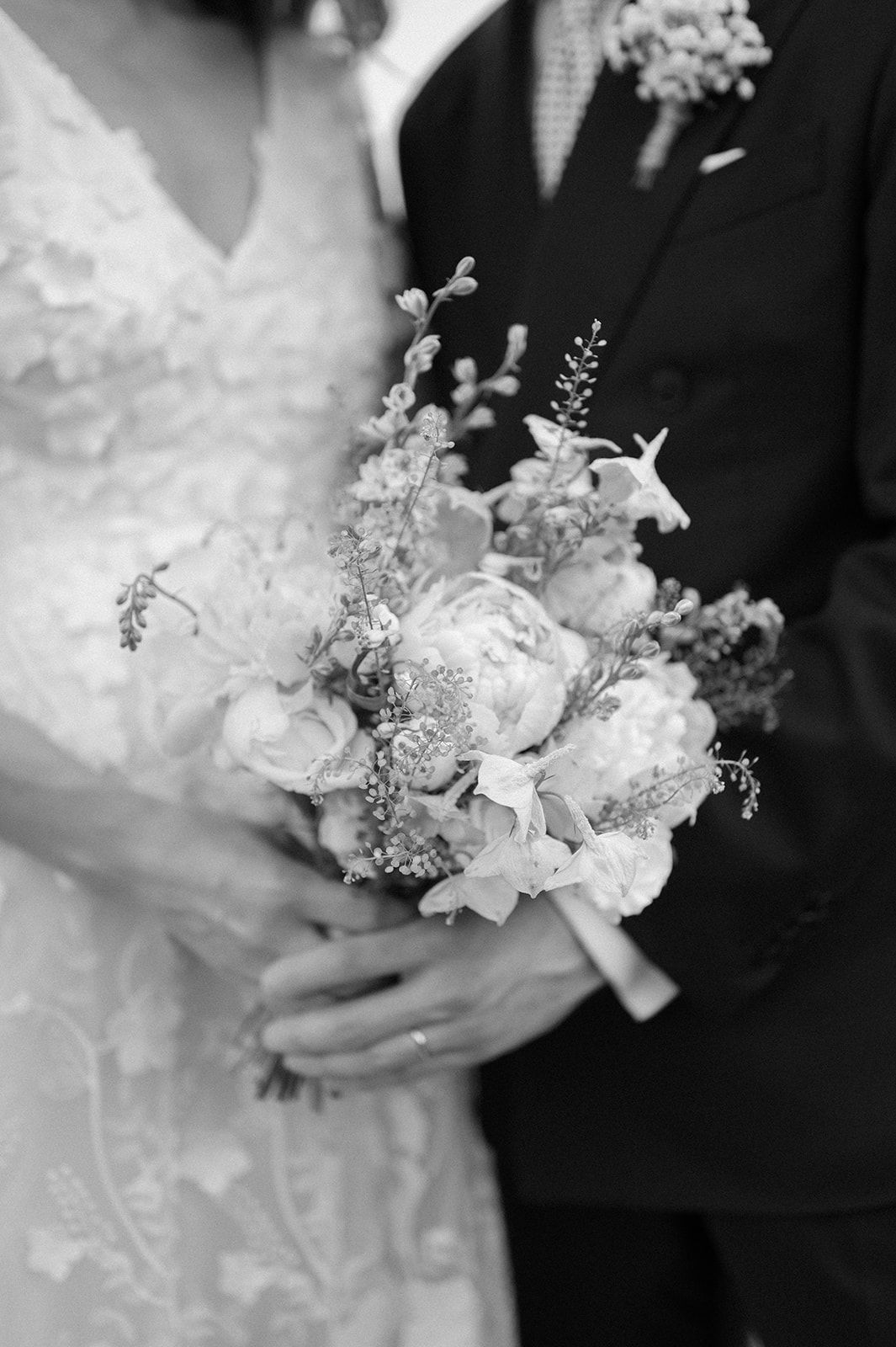 Black and white detail shot of wedding bouquet featuring white flowers and delicate greenery.