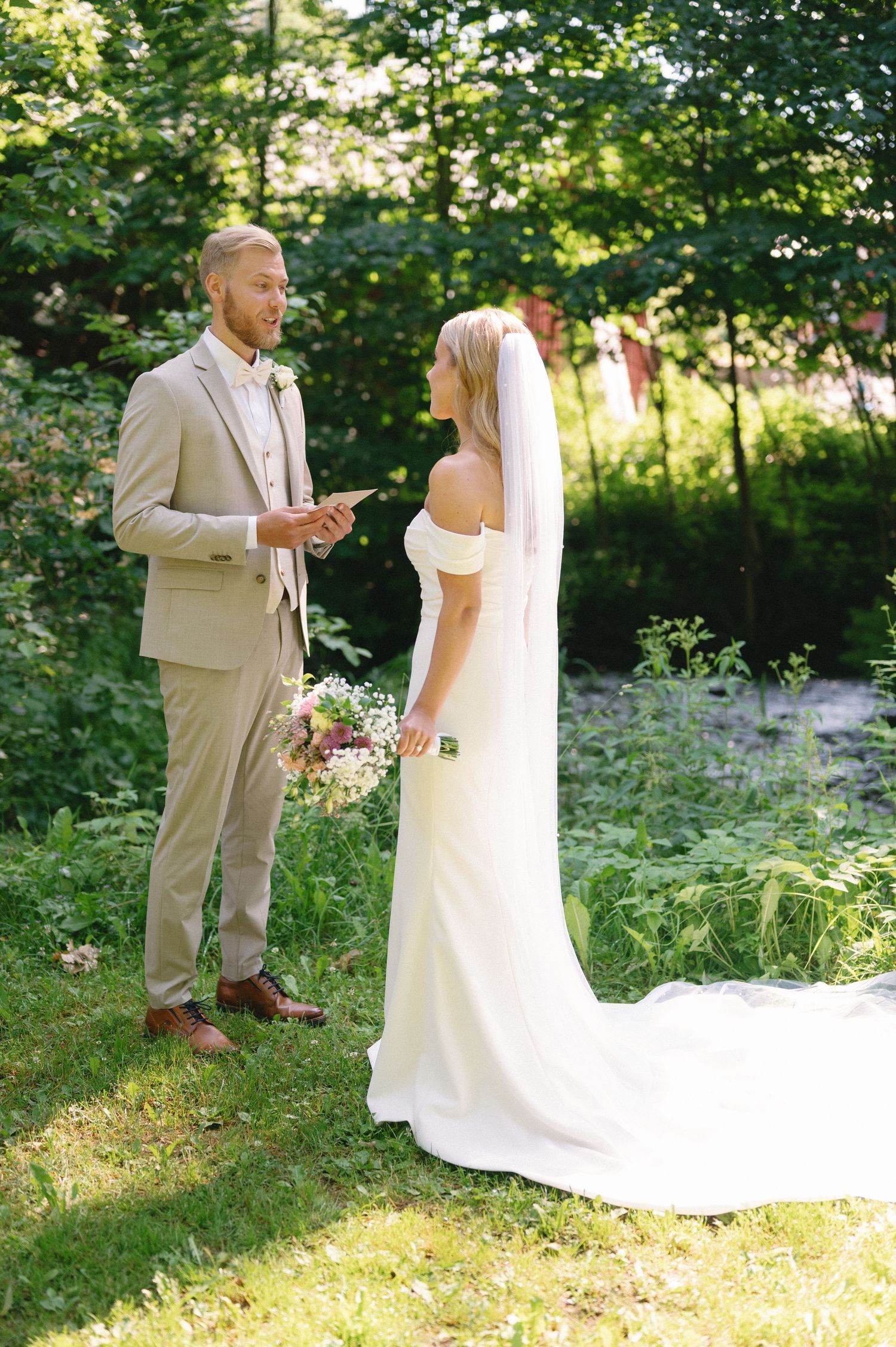 Wedding couple sharing a private moment in a sunlit garden with greenery.