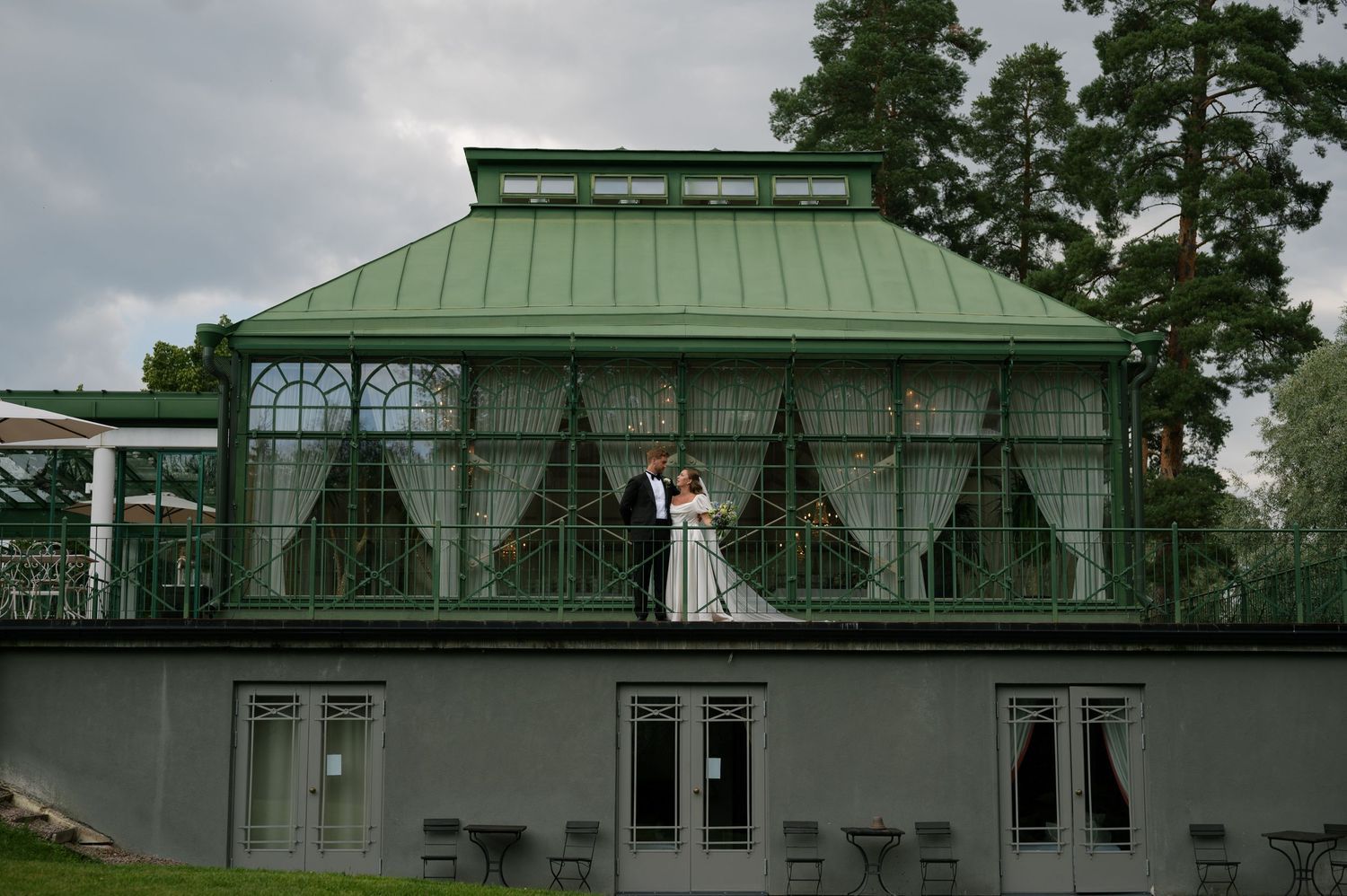 Panoramic view of a stately green-roofed mansion with classical architecture and landscaped grounds.