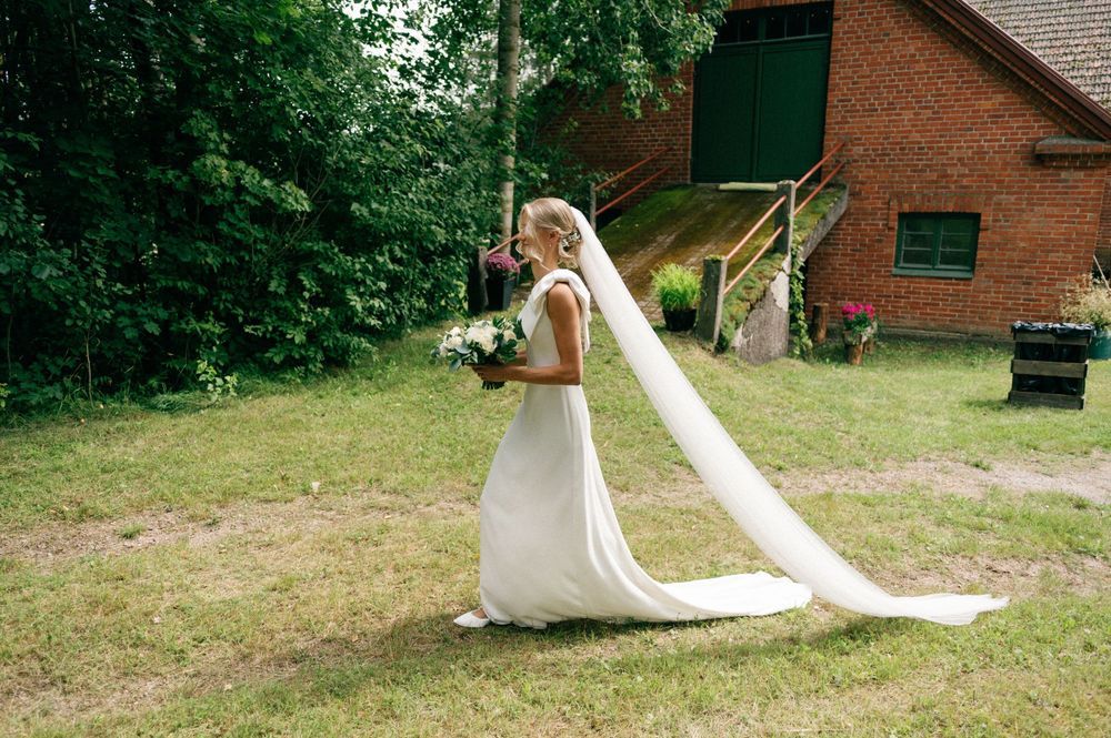 Elegant wedding couple poses together in a lush garden setting with flowing white dress and classic tuxedo.