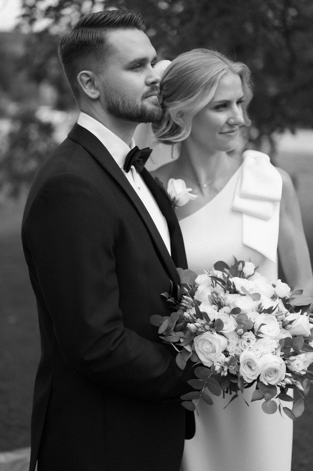 An elegant black and white wedding photo showing a couple with a white floral bouquet.