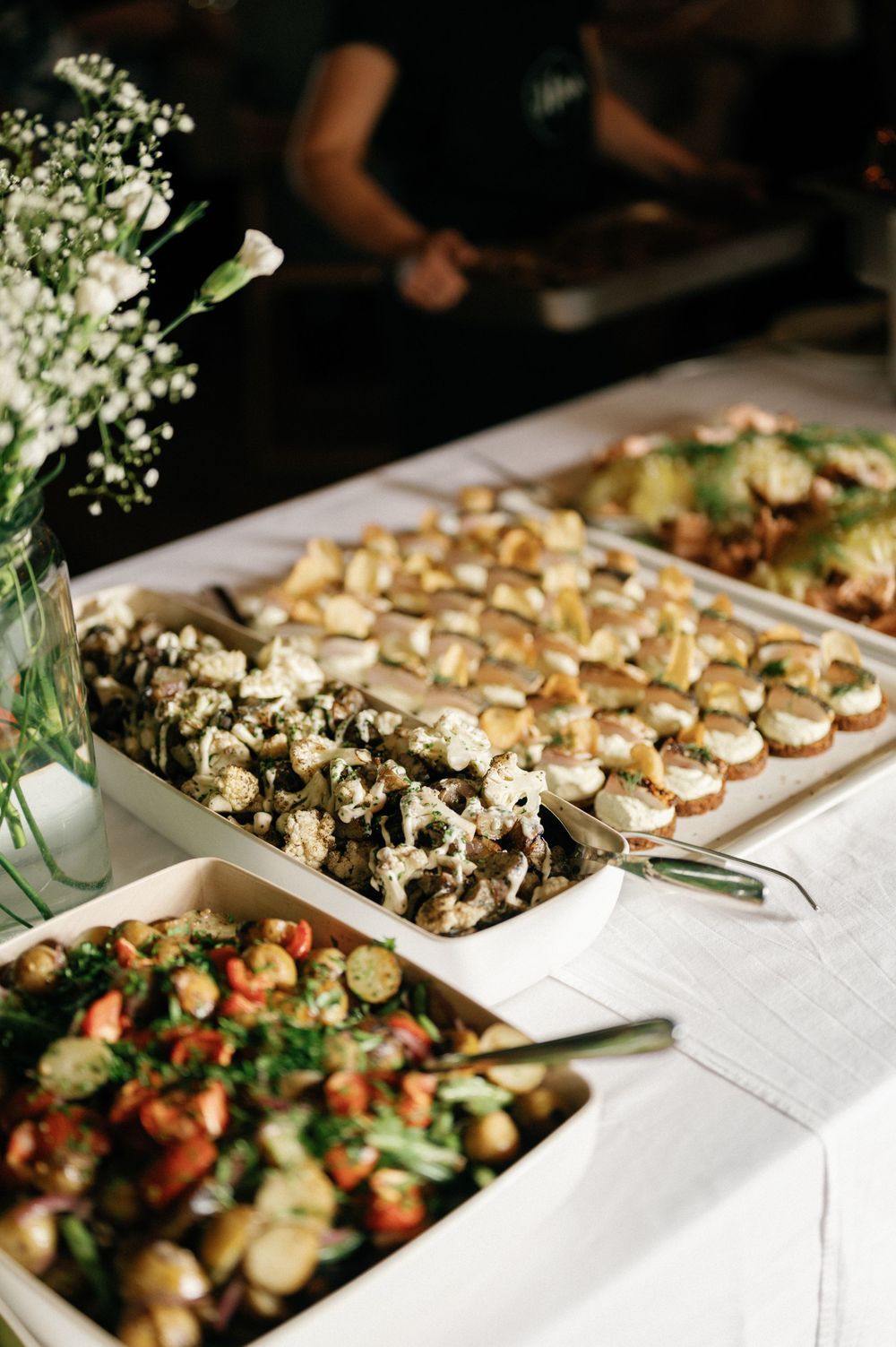 Elegant appetizer display featuring rows of hors d'oeuvres on white serving platters with fresh herbs.