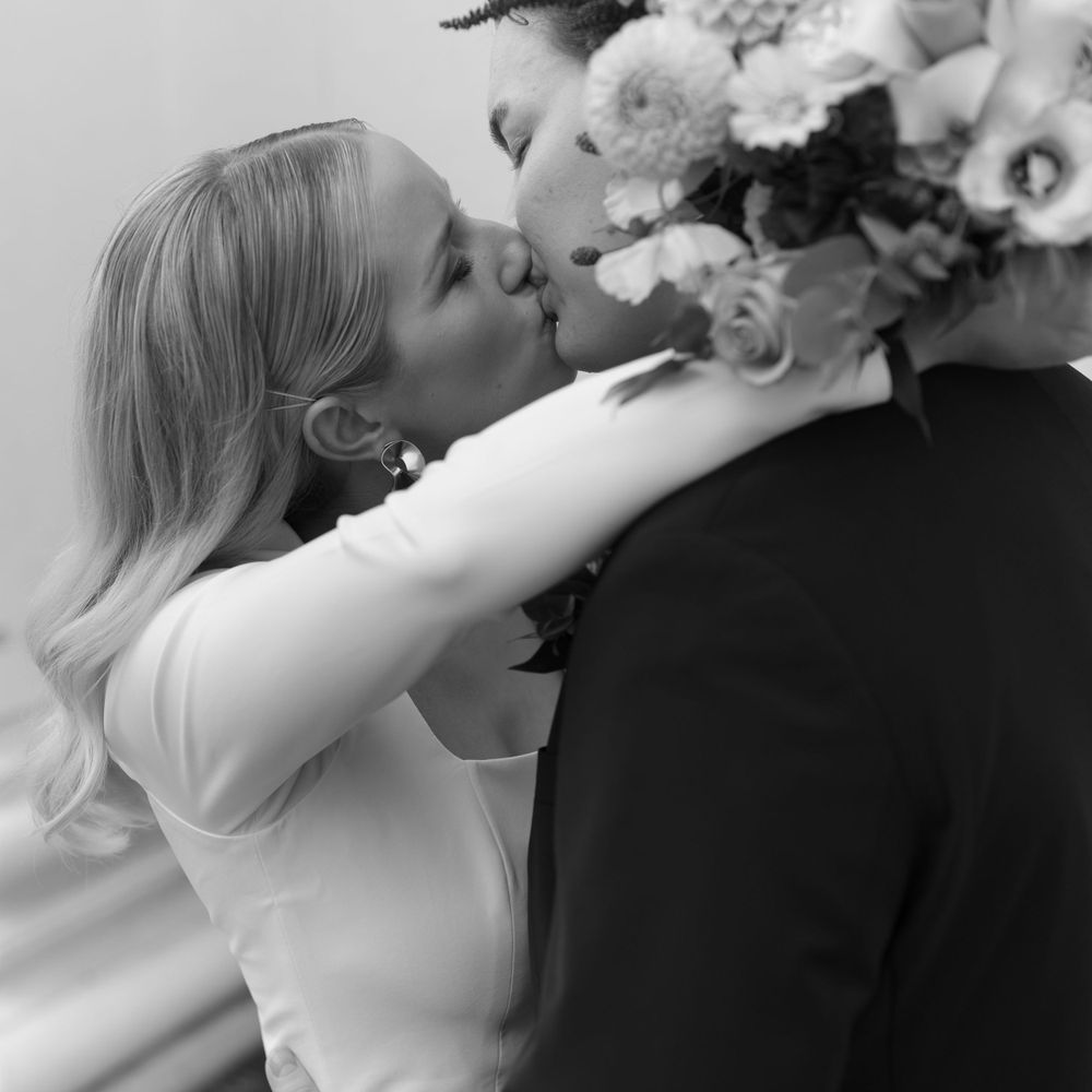 A black and white romantic moment captured between newlyweds with a bouquet of flowers.